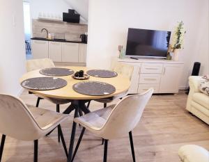 a dining room with a table and chairs and a tv at Apartament Storczykowy in Frombork