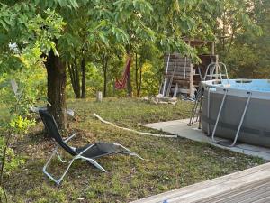 a chair sitting in the grass next to a boat at Romantisches Tiny House mit Pool and Air Condition in Tržec