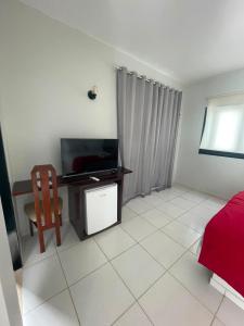 a living room with a television and a chair at Villa Veríssimo in Jericoacoara