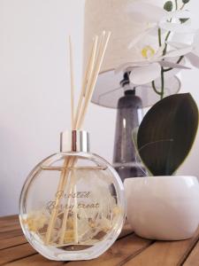 a glass bottle on a table with a plant and a lamp at Apartament Storczykowy in Frombork