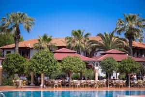 a resort with a swimming pool and palm trees at Ali Bey Club & Park in Kizilagac