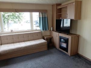 a living room with a couch and a flat screen tv at Elli-Roo's cabin in Hartley