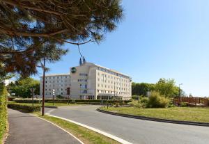 a large white building with a flag on top of it at B&B HOTEL Paris Roissy CDG Aéroport in Roissy-en-France