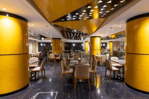 a restaurant with yellow columns and tables and chairs at Grand Plaza Hotel - Takhasosi Riyadh in Riyadh