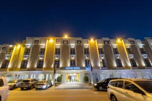 a large building with cars parked in a parking lot at Grand Plaza Hotel - Takhasosi Riyadh in Riyadh