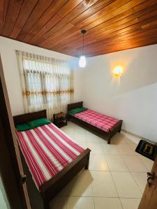 a room with two beds and a wooden ceiling at The Shire in Kandy