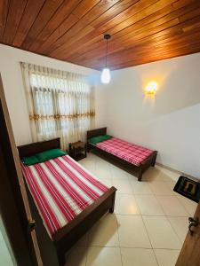 two beds in a room with a wooden ceiling at The Shire in Kandy +28 photos