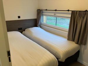 two beds in a room with a window at Resort Kagerplassen in Warmond