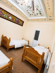 a room with two beds and a ceiling with a painting at Shahina in Samarkand