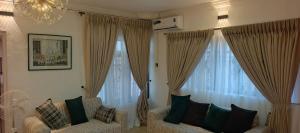 ein Wohnzimmer mit zwei Sesseln und zwei großen Fenstern in der Unterkunft Harlington Duplex in Akitan