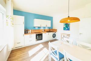 a kitchen with white cabinets and a dining table at Das Schneckenhaus EG in Lathen +4 photos