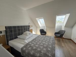 a bedroom with a bed with two chairs and two windows at Stary Tartak in Iława