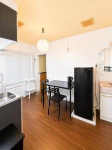 a kitchen with a table and a black refrigerator at Local LifeYOMITAN in Yomitan