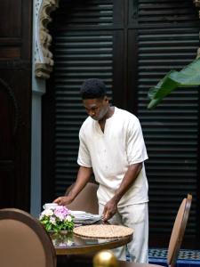 a man standing next to a table with a plate at Dar Lalzohra in Rabat
