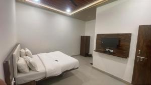 a bedroom with a bed and a tv on the wall at The Byke Retreat - Laxmi Resort - Pan India Pure Veg Hotel Chain in Matheran