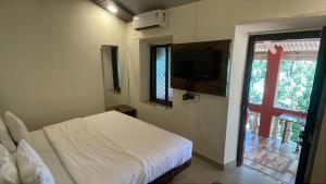 a bedroom with a bed and a tv and a window at The Byke Retreat - Laxmi Resort - Pan India Pure Veg Hotel Chain in Matheran +9 photos