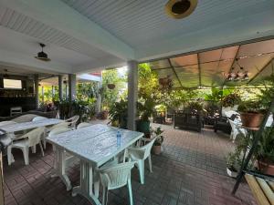 a patio with white tables and chairs and plants at Ios Guest House 2 in Kobuleti