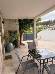 a patio with a glass table and chairs at Casa Videira in Gouveia