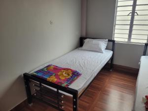 a small bed in a room with a window at Aama Ghar Siliguri in Siliguri