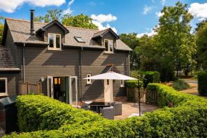 a house with an umbrella and a patio at Luxury Cottage in the New Forest with Log Burner in Redlynch