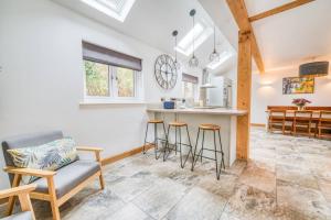 a kitchen and living room with a counter and stools at Luxury Cottage in the New Forest with Log Burner in Redlynch