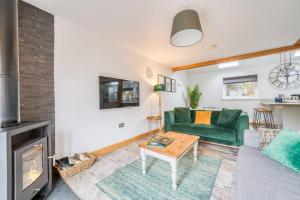 a living room with a green couch and a fireplace at Luxury Cottage in the New Forest with Log Burner in Redlynch