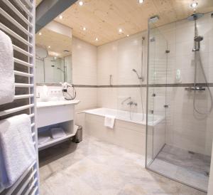 een badkamer met een douche, een bad en een wastafel bij Wellnesshotel Sonnenhof & Sonnhalde in Ühlingen-Birkendorf