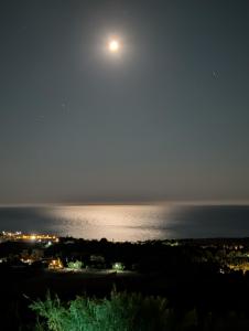 a full moon over the water at night at Villa Thea Ferienhaus mit Meerblick auf Kefalonia in Sarláta