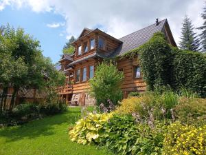 a wooden house with a garden in front of it at Kitajówka in Bańska Wyżna