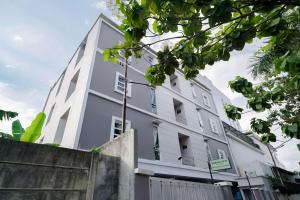 a white building with a fence in front of it at Urbanview Hotel Bari Syariah Palembang By RedDoorz in Sukarami