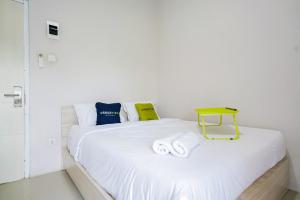 a white bed with a yellow table on it at Urbanview Hotel Bari Syariah Palembang By RedDoorz in Sukarami