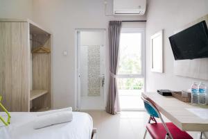 a bedroom with a bed and a desk and a window at Urbanview Hotel Bari Syariah Palembang By RedDoorz in Sukarami