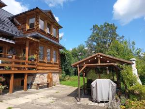 a wooden house with a pavilion in front of it at Kitajówka in Bańska Wyżna