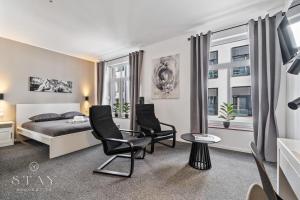 a bedroom with a bed and two chairs at Hotel Stay Properties in Luxembourg