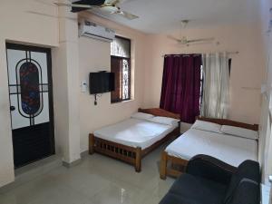 a room with two beds and a tv and a couch at krishnageeth 4bedroom villa in Guruvāyūr