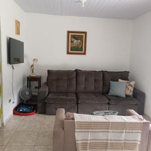 a living room with a brown couch and a tv at Casa amarela in Gonçalves