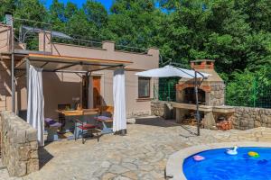 a patio with a pool and an umbrella and a grill at Villa Adry 2 in Bribir