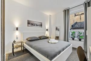 a white bedroom with a bed and a window at Hotel Stay Properties in Luxembourg