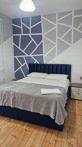 a bedroom with a bed with a blue and white wall at Titi's home Velipoje in Velipojë