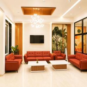 a living room with red couches and a tv at Hotel Mangla Inn - Dwarka in Dwarka