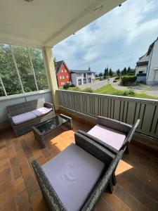 a porch with chairs and tables on a balcony at Bodenseeapartments in Friedrichshafen