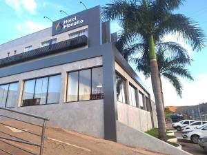 a building with a palm tree in front of it at Hotel Planalto 2 in Governador Valadares