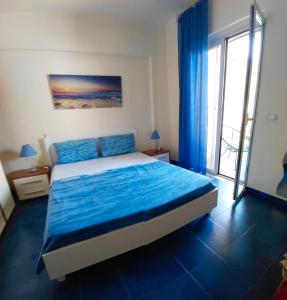 a bedroom with a bed with blue sheets and a window at SANT'ALESSIO BEACH HOLIDAY in SantʼAlessio Siculo