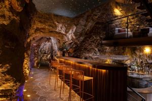 a bar with a stone wall and chairs in a cave at Hotel More in Dubrovnik