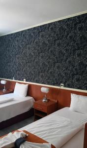 a hotel room with two beds and a wall with wallpaper at Atlantic Hotel in Budapest