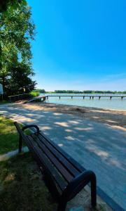 a park bench sitting next to a body of water at Domki nad jeziorem in Łasin