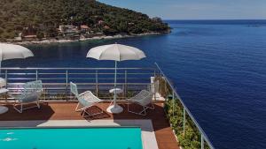 a balcony with chairs and an umbrella next to the water at Hotel More in Dubrovnik