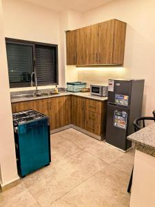 a kitchen with wooden cabinets and a black refrigerator at Résidence Leyla in Abidjan
