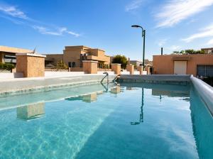 ein Swimmingpool mit blauem Wasser vor einigen Gebäuden in der Unterkunft וילת אתרוג - וילה וצימר מושלמים עם בריכה באשלים in Ashalim
