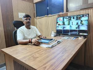 a man sitting at a desk with a computer at hotelnishainn in Rānchī